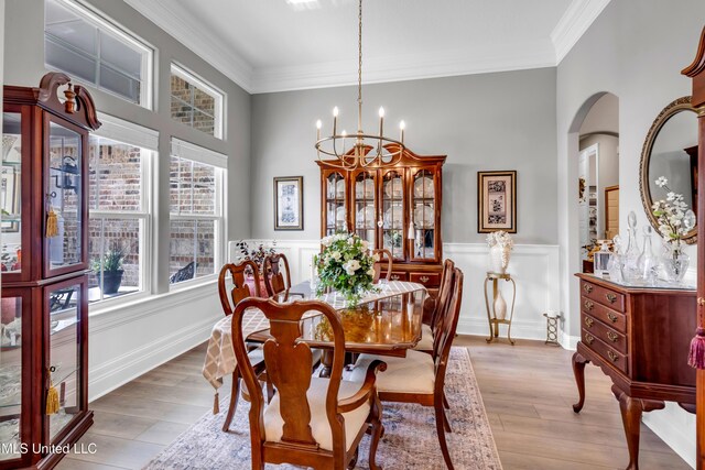 12578 Alphabet Rd, Gulfport, MS 39503 - dining space with arched walkways, ornamental molding, a chandelier, wood finished floors, and a wainscoted wall