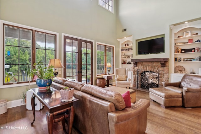 4666 Eiffel Ln, Nesbit, MS 38651 - living room featuring built in features, french doors, wood finished floors, a stone fireplace, and a towering ceiling