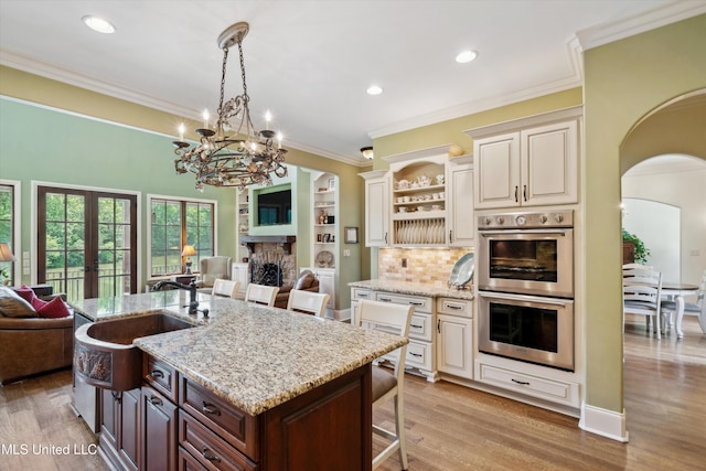 4666 Eiffel Ln, Nesbit, MS 38651 - kitchen featuring stainless steel double oven, open floor plan, a sink, a breakfast bar area, and crown molding