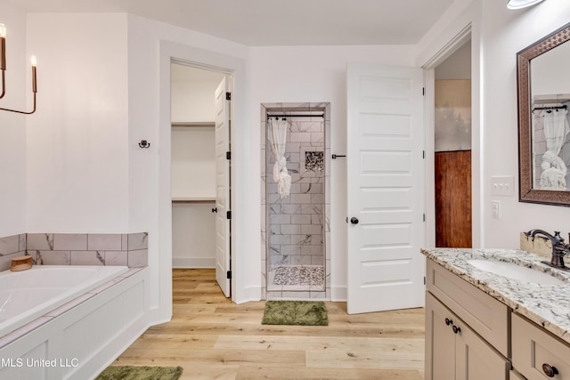 bathroom featuring hardwood / wood-style floors, vanity, and plus walk in shower