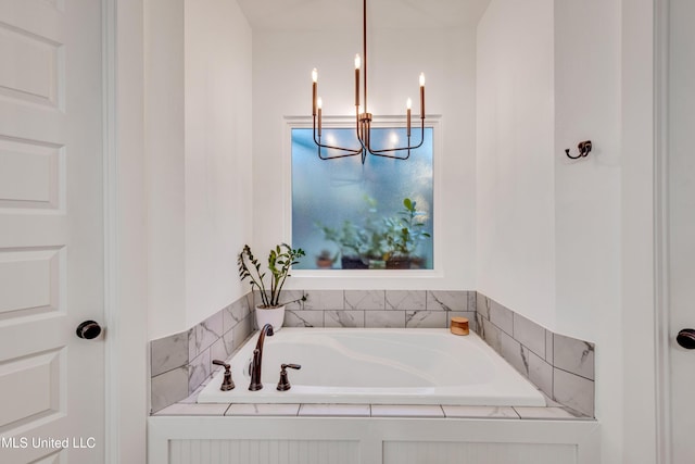 bathroom featuring a chandelier and a relaxing tiled tub