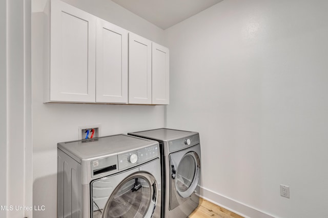 clothes washing area featuring washer and dryer, cabinets, and light hardwood / wood-style floors