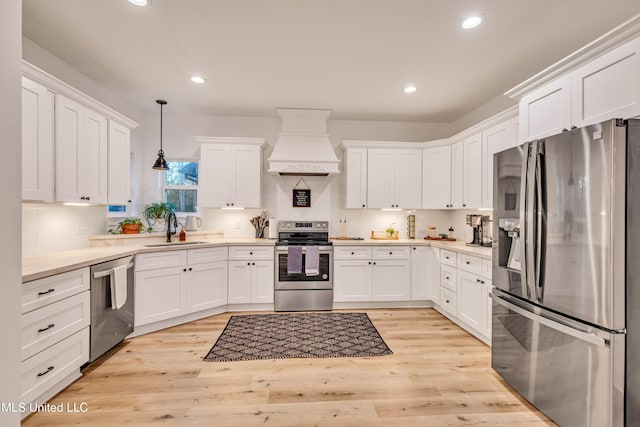 kitchen featuring sink, hanging light fixtures, stainless steel appliances, white cabinets, and custom range hood