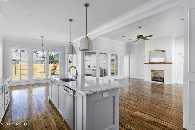 kitchen with light stone countertops, sink, dishwasher, pendant lighting, and dark hardwood / wood-style floors