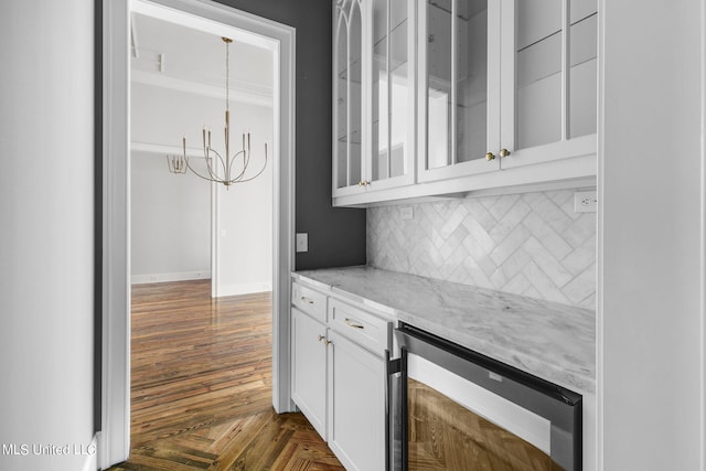 bar featuring wine cooler, a notable chandelier, white cabinetry, light stone counters, and tasteful backsplash