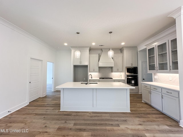 kitchen with wood finished floors, appliances with stainless steel finishes, custom exhaust hood, and tasteful backsplash