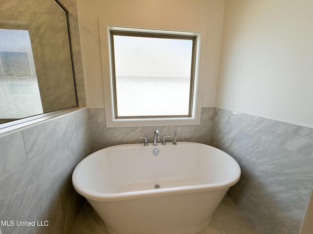 bathroom with a freestanding bath and tile walls