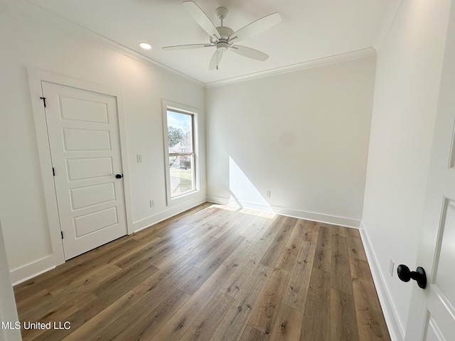 spare room featuring recessed lighting, wood finished floors, a ceiling fan, baseboards, and crown molding