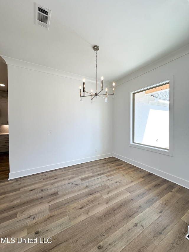 unfurnished dining area with baseboards, visible vents, and wood finished floors