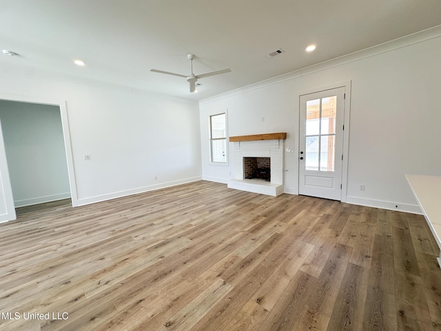 unfurnished living room featuring a fireplace, wood finished floors, visible vents, and crown molding