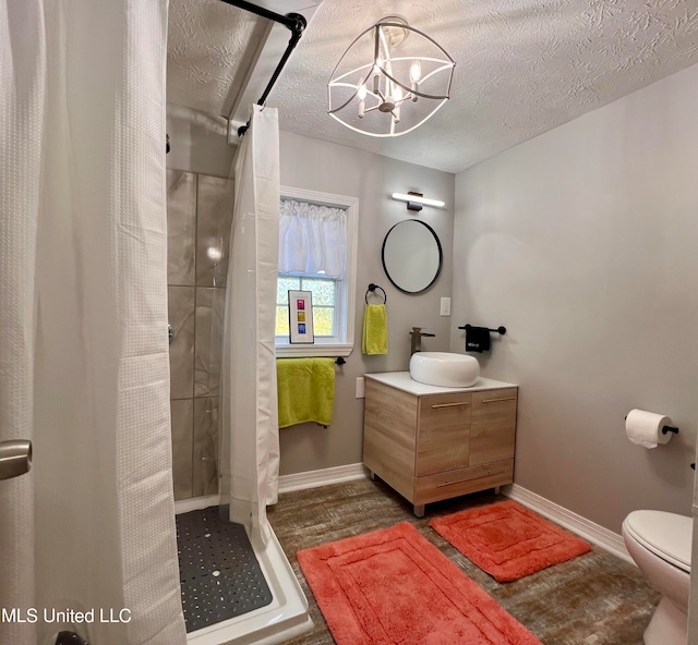 bathroom featuring vanity, toilet, a textured ceiling, a notable chandelier, and curtained shower