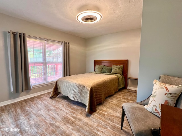 bedroom featuring a textured ceiling and light hardwood / wood-style flooring