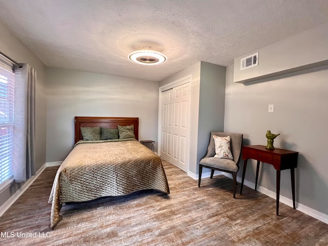 bedroom with hardwood / wood-style flooring, a textured ceiling, and a closet