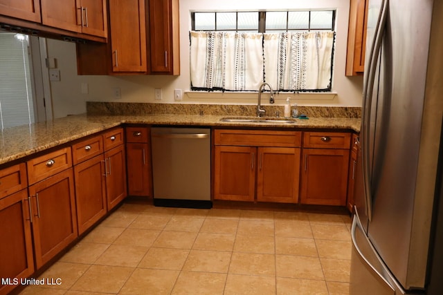 kitchen featuring appliances with stainless steel finishes, kitchen peninsula, sink, and light stone counters