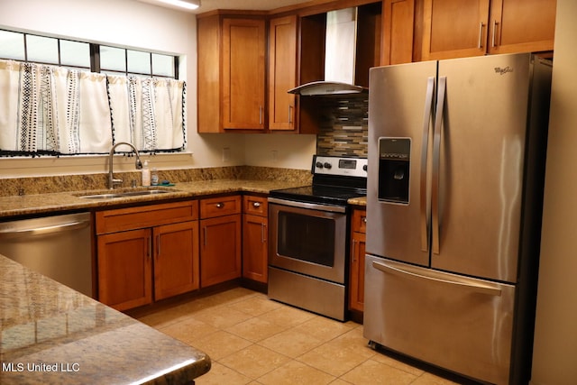 kitchen with wall chimney range hood, light stone counters, light tile patterned flooring, sink, and stainless steel appliances