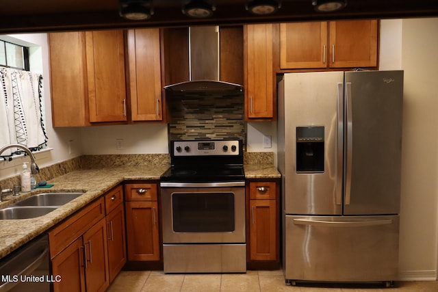 kitchen featuring wall chimney range hood, light tile patterned flooring, appliances with stainless steel finishes, sink, and light stone counters