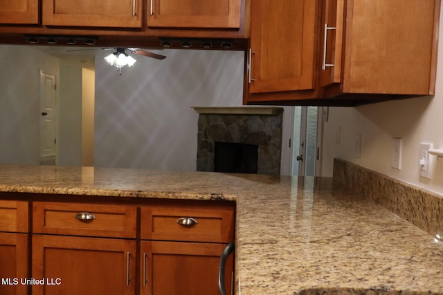 kitchen with light stone counters, a fireplace, and ceiling fan