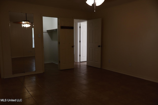 unfurnished bedroom featuring a closet, dark tile patterned floors, and ceiling fan