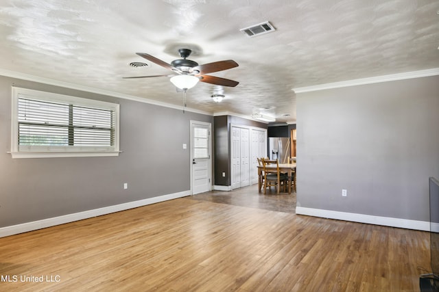 unfurnished living room with crown molding, hardwood / wood-style flooring, a textured ceiling, and ceiling fan