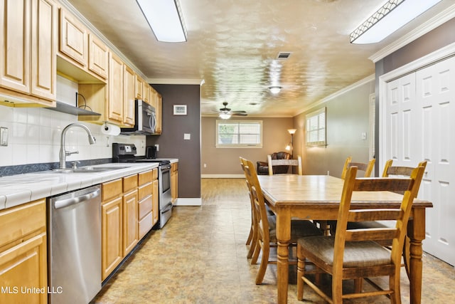 kitchen featuring tasteful backsplash, appliances with stainless steel finishes, sink, tile counters, and ornamental molding