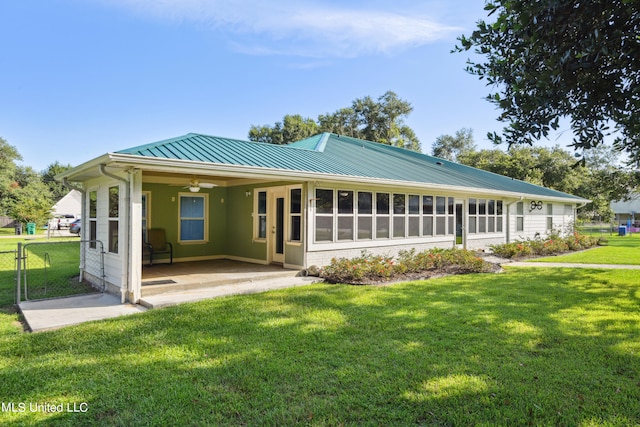 rear view of property with a sunroom, a lawn, and ceiling fan