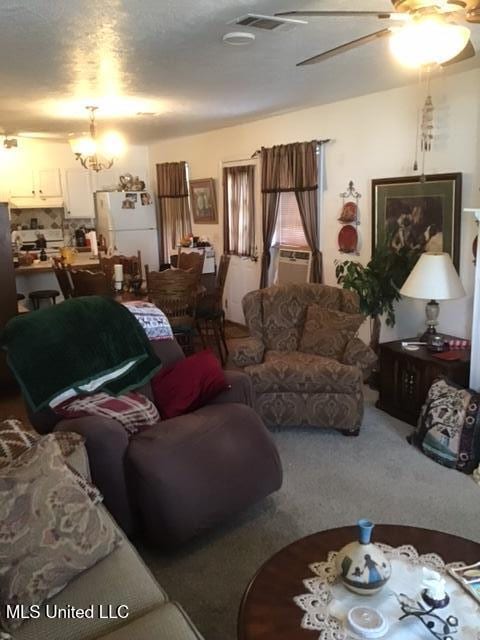 living room featuring ceiling fan with notable chandelier, cooling unit, and carpet floors