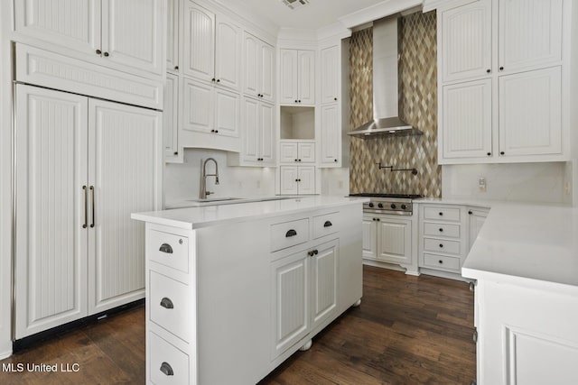 kitchen with stainless steel gas stovetop, backsplash, dark wood-type flooring, white cabinets, and wall chimney range hood