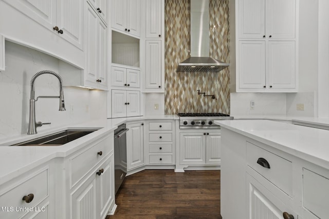 kitchen with dark hardwood / wood-style flooring, stainless steel appliances, sink, wall chimney range hood, and white cabinetry