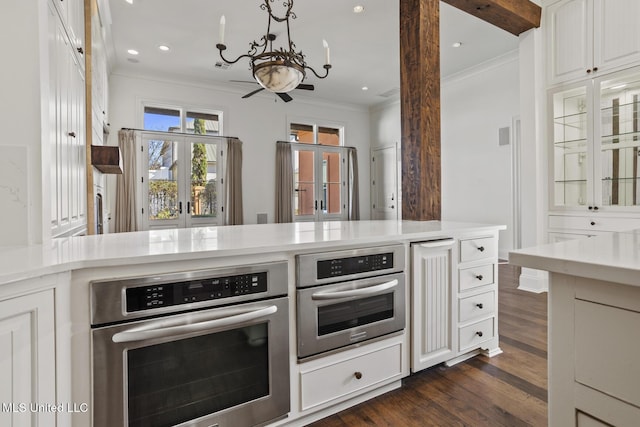 kitchen featuring white cabinets, dark hardwood / wood-style flooring, an inviting chandelier, and stainless steel oven