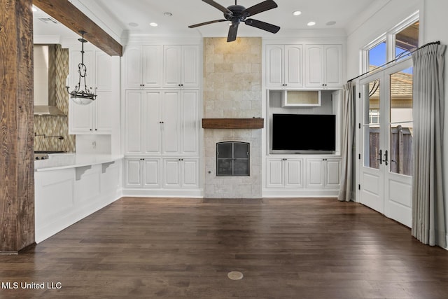 unfurnished living room with a fireplace, ornamental molding, ceiling fan, and dark wood-type flooring