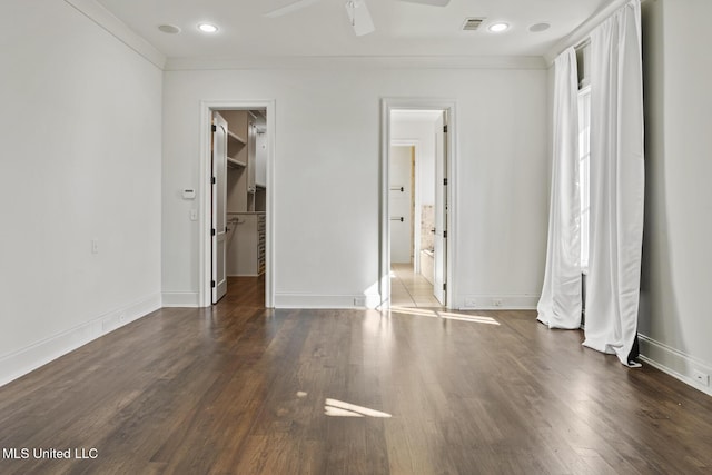 unfurnished bedroom with dark hardwood / wood-style flooring, a walk in closet, a closet, and ceiling fan