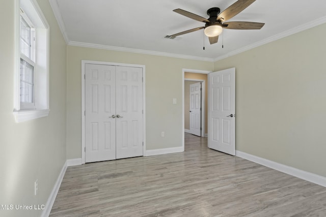 unfurnished bedroom with ornamental molding, ceiling fan, a closet, and multiple windows