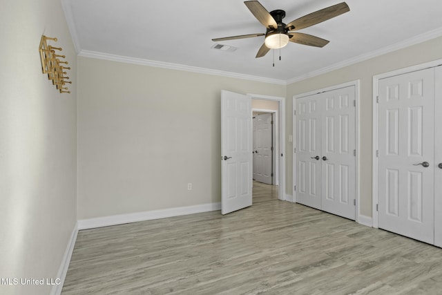 unfurnished bedroom with ornamental molding, ceiling fan, light hardwood / wood-style floors, and multiple closets