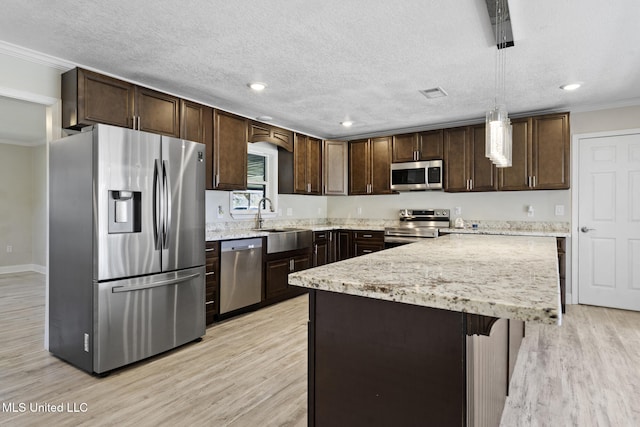 kitchen with sink, decorative light fixtures, light wood-type flooring, crown molding, and appliances with stainless steel finishes