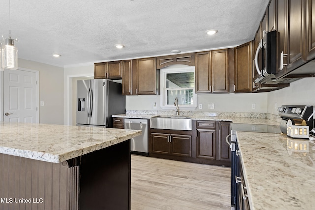 kitchen featuring stainless steel appliances, sink, a textured ceiling, a center island, and hanging light fixtures