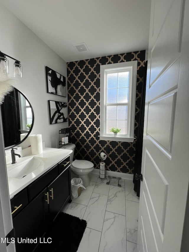 bathroom featuring visible vents, vanity, marble finish floor, toilet, and wallpapered walls
