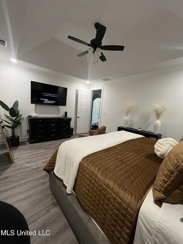 bedroom featuring a ceiling fan, arched walkways, visible vents, and wood finished floors