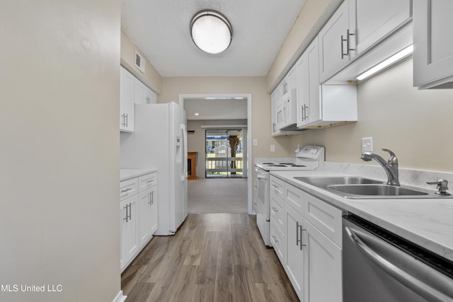 295 Highpoint Dr, Diamondhead, MS 39525 - kitchen featuring wood finished floors, white appliances, a sink, white cabinetry, and visible vents