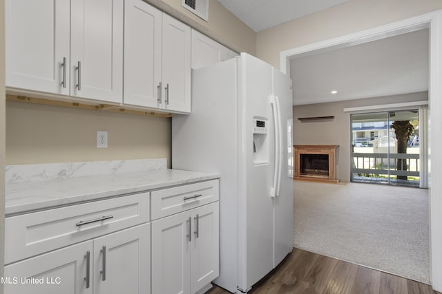 295 Highpoint Dr, Diamondhead, MS 39525 - kitchen with white fridge with ice dispenser, white cabinetry, visible vents, a fireplace with raised hearth, and open floor plan