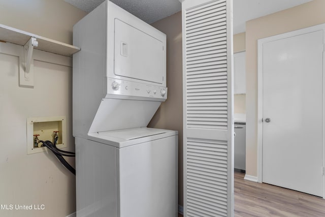 laundry area featuring light hardwood / wood-style floors, a textured ceiling, and stacked washer and clothes dryer