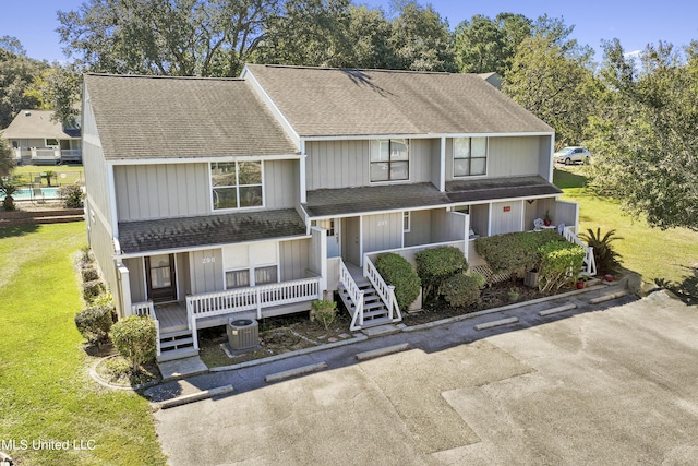 295 Highpoint Dr, Diamondhead, MS 39525 - view of front of house with a front yard, central air condition unit, covered porch, and roof with shingles