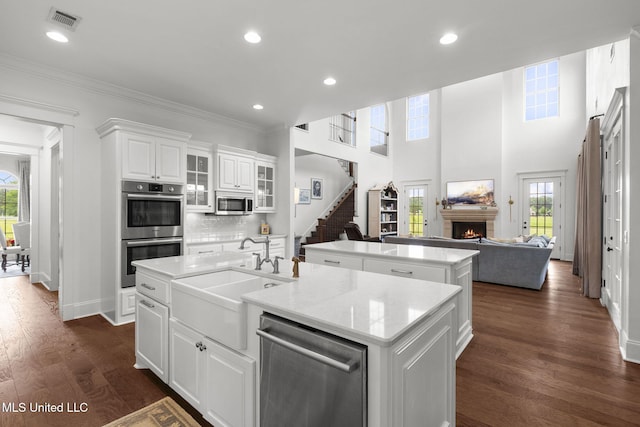 1053 Woodbridge Dr, Brandon, MS 39047 - kitchen featuring a center island with sink, stainless steel appliances, a warm lit fireplace, open floor plan, and crown molding