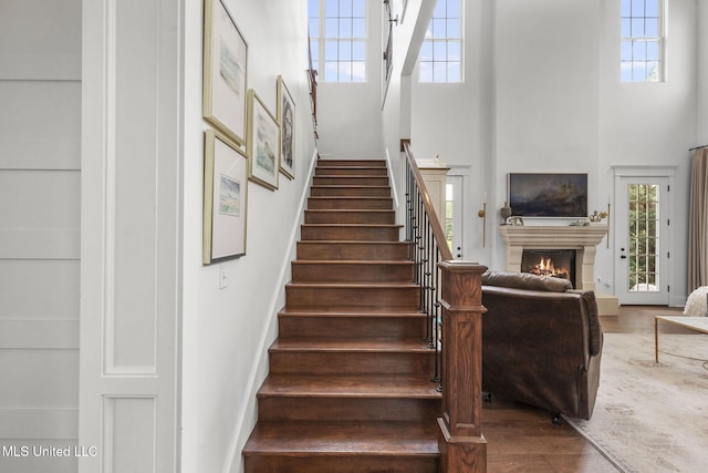 1053 Woodbridge Dr, Brandon, MS 39047 - stairs with a high ceiling, wood finished floors, a warm lit fireplace, and plenty of natural light