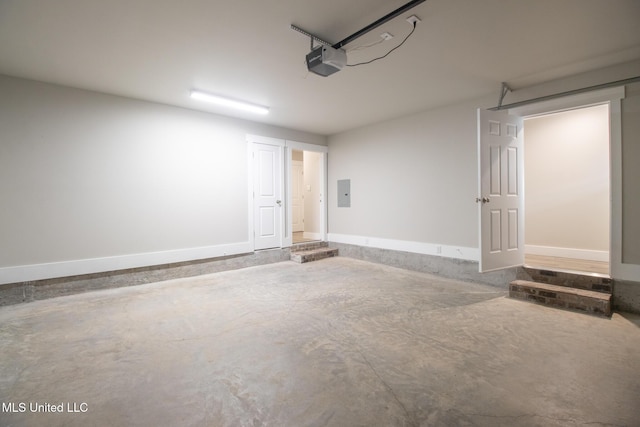 garage with a garage door opener, electric panel, and baseboards