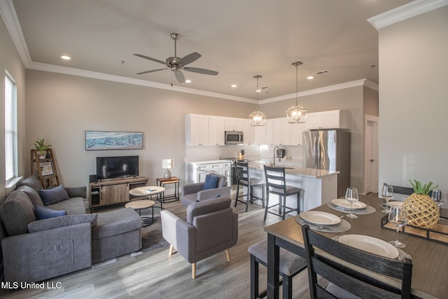 living area featuring ornamental molding, light wood-type flooring, visible vents, and ceiling fan