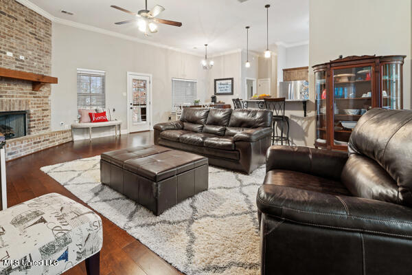 living room with a fireplace, ornamental molding, wood-type flooring, and a high ceiling