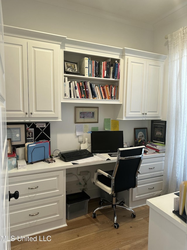 office space featuring wood finished floors, built in study area, and crown molding