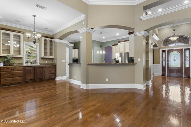5578 E Diamondhead Dr, Diamondhead, MS 39525 - kitchen with stainless steel refrigerator with ice dispenser, ornate columns, arched walkways, dark wood-type flooring, and glass insert cabinets