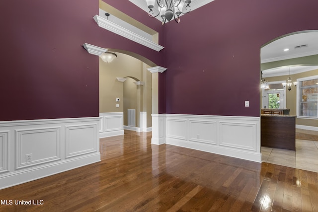5578 E Diamondhead Dr, Diamondhead, MS 39525 - unfurnished room with a chandelier, arched walkways, ornamental molding, wood finished floors, and ornate columns