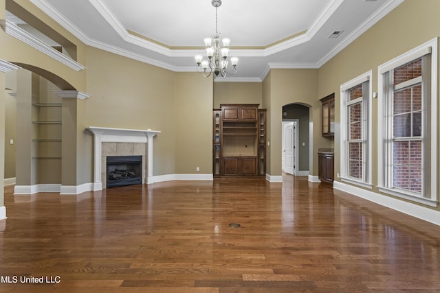5578 E Diamondhead Dr, Diamondhead, MS 39525 - unfurnished living room featuring arched walkways, a tray ceiling, wood finished floors, a chandelier, and crown molding